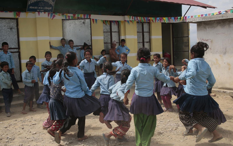 A group of girls in blue uniforms forming a circle while playing.